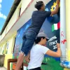 A photo of two volunteers painting a wall mural.