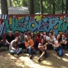A photograph of volunteers smiling and eating popsicles in front of a sign which reads "Heideruh."